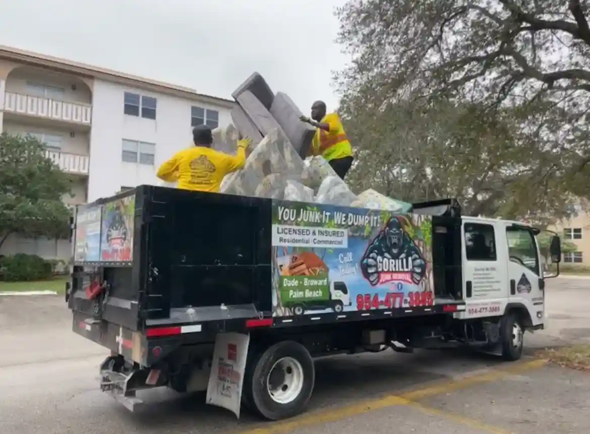 Gorilla Junk Removal crew loading bulky items like mattresses into their truck in a Florida apartment complex parking lot.