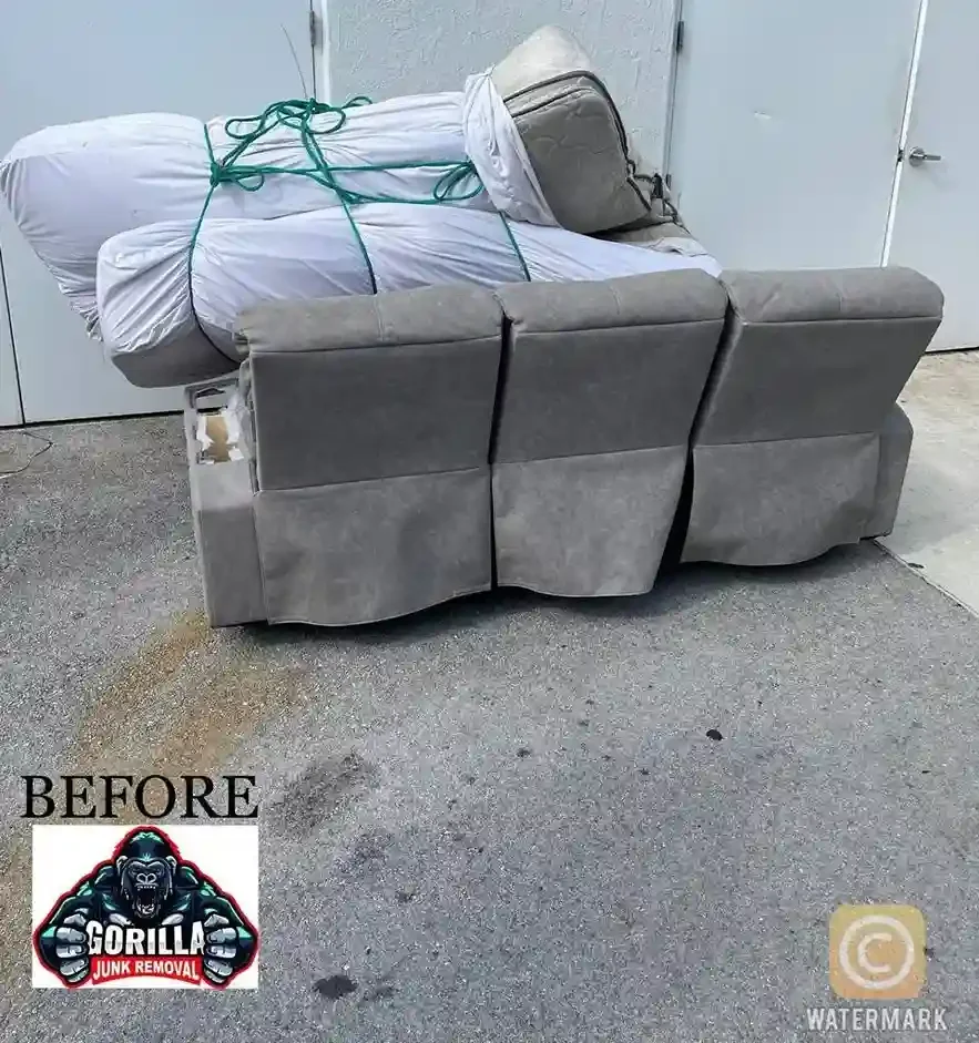 Bulky grey couch and wrapped mattresses blocking a commercial doorway before professional junk removal service