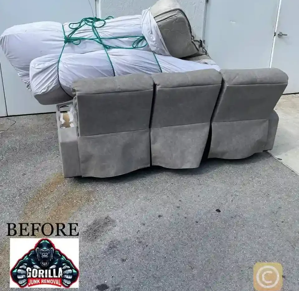 Bulky grey couch and wrapped mattresses blocking a commercial doorway before professional junk removal service